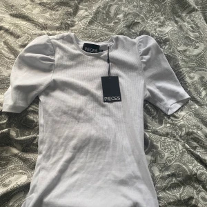 Vit T-shirt med puff-armar - Säljer nu denna fina tröja då den inte kommer till användning. Tröjan har aldrig varit använd utan bara testats. Lappen sitter kvar också. 