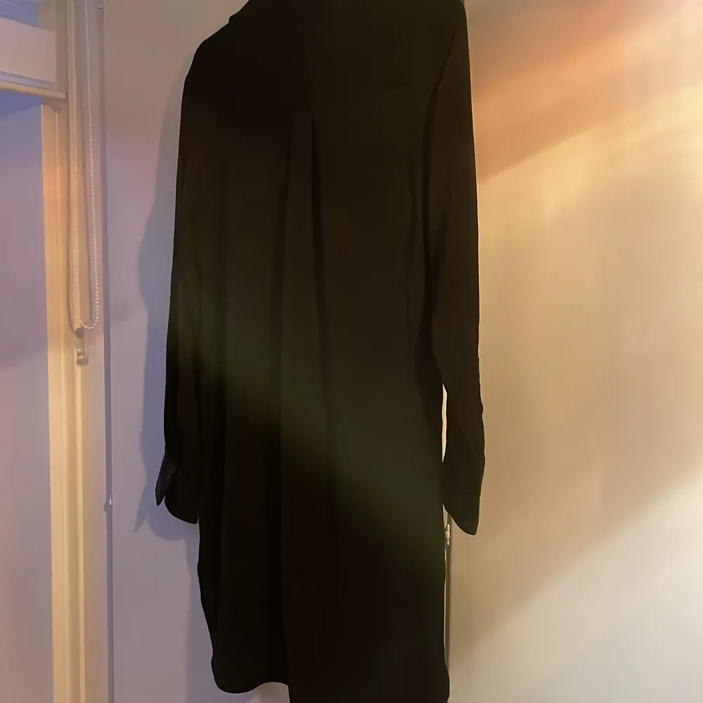 En svart lång klänning i nyskick, prislappen sitter kvar. sitter Super snyggt och om man vill lyxa till det lite kan man knyta t.ex ett bälte i midjan. Skönt tyg.. Mekot.
