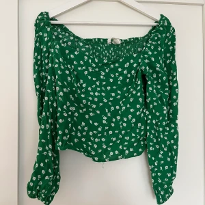 Grön blommig topp - Fin långärmad grön topp med små vita blommor på, använd bara ett fåtal gånger! Inte min stil längre så därför säljer jag den:) 