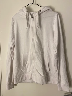 Munkjacka - En vit munkjacka med dragkedja och fickor.