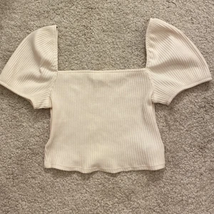 Topp  - En vit topp från hm. Använd en gång. Kort topp med fyrkantig urringning och puffiga ärmar.