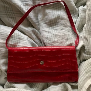 Röd baguette väska - Säljer nu min helt oanvända röda baguette väska! Väskan är mörkröd med ormskinnsmaterial! Den har även ett stort fack inuti samt en mindre fack med dragkedja. Köptes för 400kr. Köparen står för frakt, priset kan diskuteras❣️💌❣️