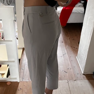 Kortare byxor från stocklm strl 36  - Gråa tunna kostymbyxor från Stockholm strl 36  Jag är 165 och byxorna slutar på halva vaden ungefär 