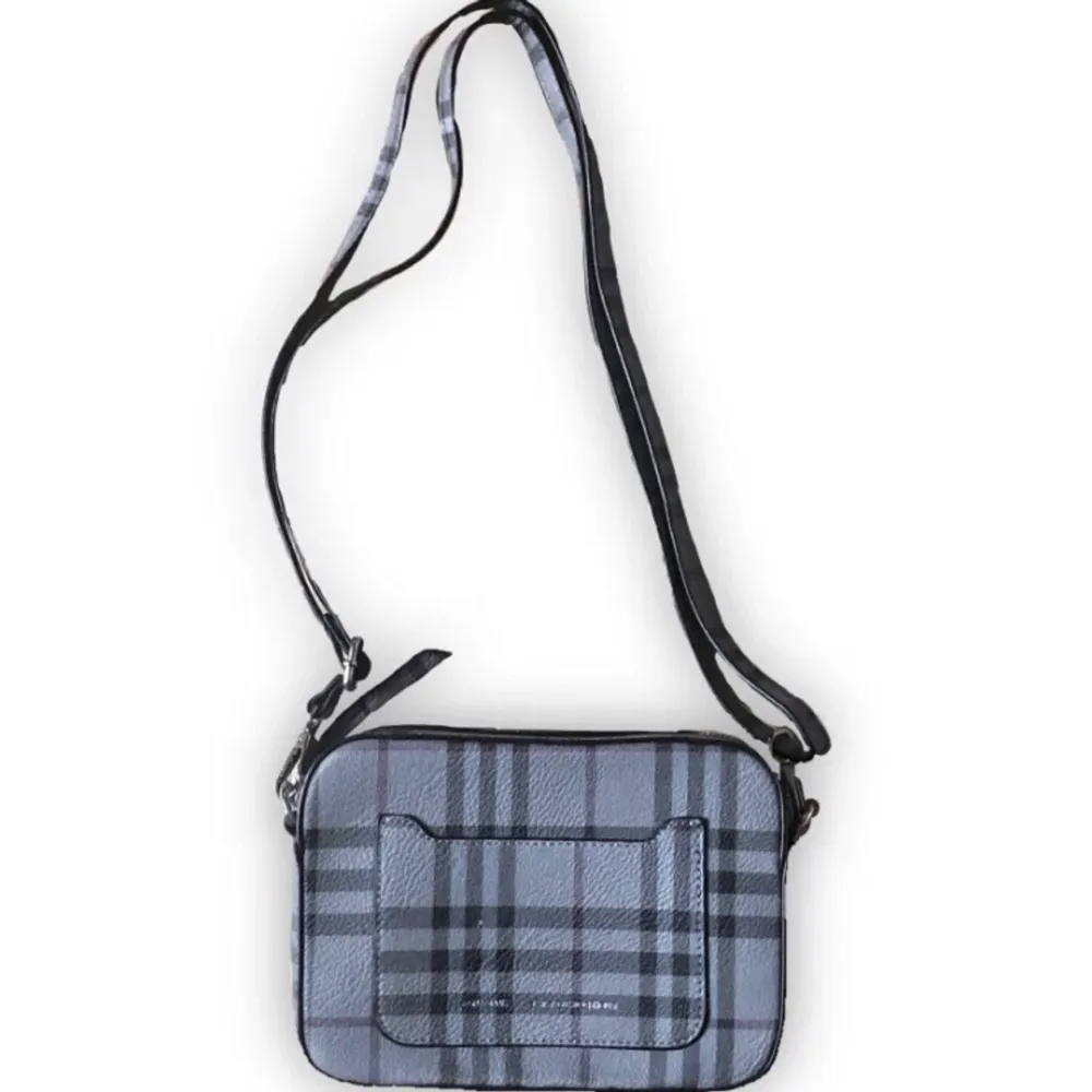 En grå rutig handväska med lila detaljer köpt från märket Don Donna 💼 🔘 Den är i konstläder och har sjysterbara band!. Väskor.