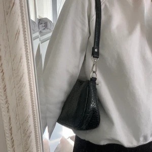 Svart axelväska  - Säljer denna svarta axelväska då den inte kommer till användning längre då jag använder större väskor nu. Har använt den del men har inga tecken på användning, den är väldigt rymlig för att vara en liten väska. OBS köparen står för frakten 
