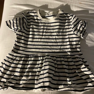 Randig t-shirt med volangkant - Det är en randig t-shirt som var väldigt trendig förra året. Den är i bra skick och är struken innan man får den!