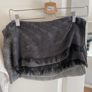 Sjal, Guess  - En fin lite lyxigare sjal till utseendet, fint skick.  Från Guess, färgerna är grå/svart 