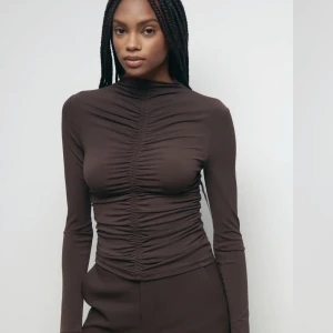 Ewelina top - ”Långärmad topp i trikå med rynkad effekt. Toppen är brun och har en figurnära passform.” Aldrig använd, prislapp finns kvar.  Ordpris: 299kr
