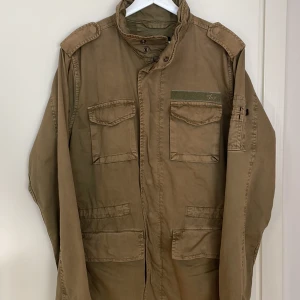 Alpha Industries vårjacka - Alpha Industries vår/sommar jacka i uppdaterad m65 modell. Regular fit. Olivgrön. Storlek M.  Sparsamt använd! 