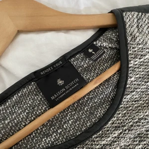 MAISON SCOTCH - melerad blus - Blus i storlek 1 (S) från märket MAISON SCOTCH. Grå/vit/beige/svart-melerad med detaljer i syntetläder. Använd få gånger, inga tecken på användning!