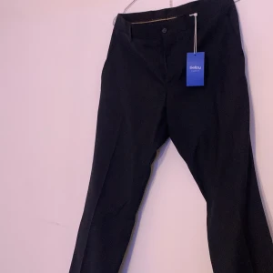 Kostym byxor  - Ett par kostym byxor som är stora i midjan och ganska långa.