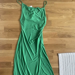 Långklänning, grön - Grön långklänning med slits och öppen rygg (korsade band i ryggen). Aldrig använd! (Prislapp kvar)