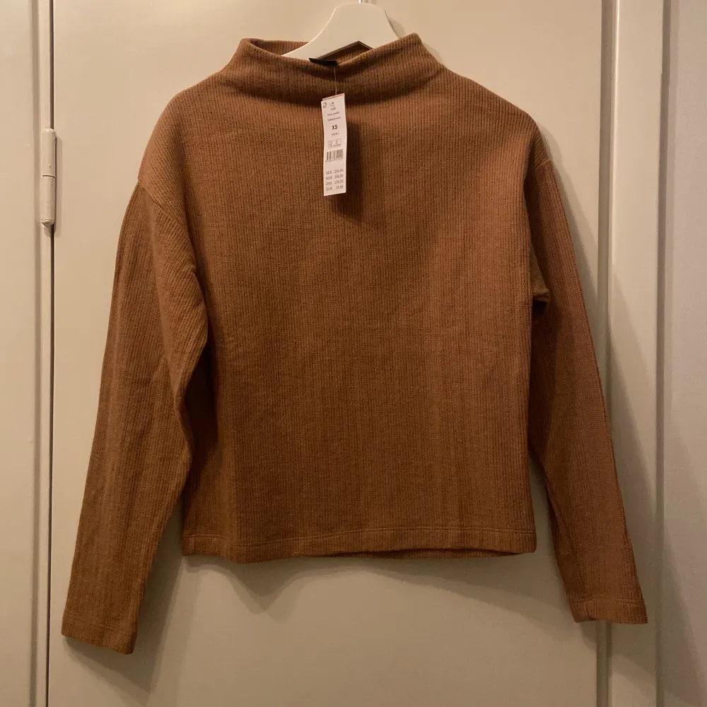 Brun/mörkbeige halvpolo från Gina Tricot, helt oanvänd med prislapp kvar. Modellen på tröjan heter Emmy sweater. Stickat.