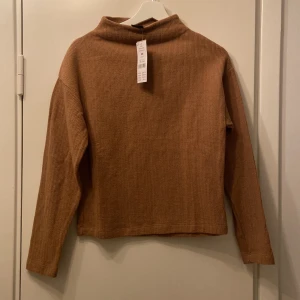 Stickad halvpolo-tröja  - Brun/mörkbeige halvpolo från Gina Tricot, helt oanvänd med prislapp kvar. Modellen på tröjan heter Emmy sweater