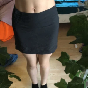 Kort kjol - En kort svart kjol med kardborreband på sidan i storlek 146/152