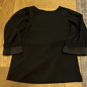 Topp med gulddetaljer - Topp med puffärmar från Lindex. Jätte fina gulddetaljer på ärmarna. Tyget är relativt tjockt och tröjan är inte mycket använd! 
