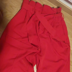 H&M röd byxor - Fina byxor med tygskarp för att knyta den till att passa just dig. Fint till julen eller annat firande.