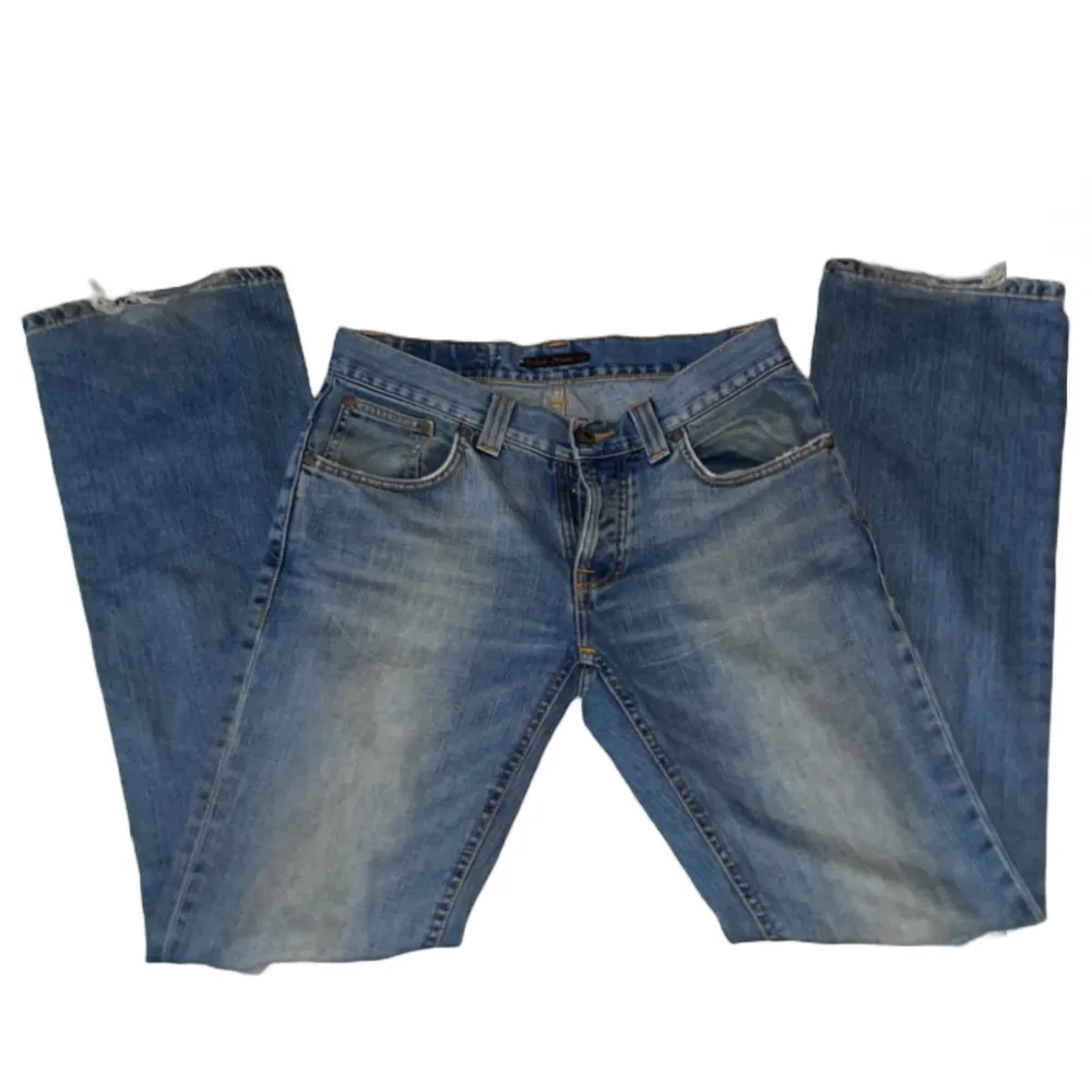 BLÅA JEANS FRÅN NUDIE JEANS         MODELL: Bootcut Ola                             MATERIAL: 100% bomull                          SKICK: Byxorna är i bra skick. De har hål på båda knäna  MÅTT: Midjemåttet är 83cm och innerbensmått är 84cm. Jeans & Byxor.