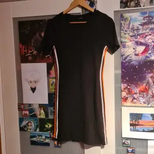 En klänning jag haft ganska länge men inte använt mer än några gånger. Det är en tight klänning med en vit och en orange linje längs med sidorna. Lappen är bortklippt så är inte säger på storleken.