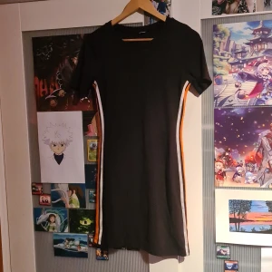 Svart bodycon klänning - En klänning jag haft ganska länge men inte använt mer än några gånger. Det är en tight klänning med en vit och en orange linje längs med sidorna. Lappen är bortklippt så är inte säger på storleken.
