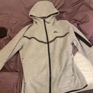 Nike tech fleece - Säljer denna nike tech fleece pga inte till användning men även i man storlek och inte kvinna. Den är i storlek S och är väldigt bekväm att ha på sig och har en luva. Nike tech fleecen är i  grå färg.