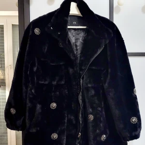 Fuskpälsjacka River Island storlek S - Svart fuskpäls jacka  med dekoration stenar, jackan är väldigt fin, stillig och mysig. Storlek S 