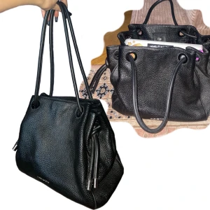 Michael Kors Väska - En superfin Michael Kors väska i svart skinn. Nypris va ca 4000kr.  Väskan må se liten ut, men är extremt rymlig! Det är min dator som ligger i den på bilden. Väldigt fint skick, trots att jag använt en del! 🥰 