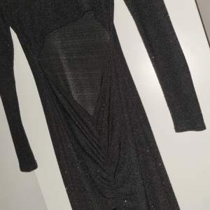 En glittrig lång klänning där ryggen är öppen vid svanken. Använd 1 gång. Köparen står för frakt (99kr)