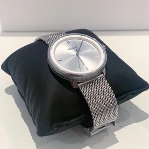 Hugo Boss (begagnad) - Pris: 1800kr Inköps pris: 2900kr  Silvrig Hugo Boss klocka med en silvrig kedja och en vinröd kedja (ingår). Klockan är i fint skick och användes i cirka 4 månader!  ———————————————— Display: analog Armbandsmaterial: ädelstål och läder Boett: ädelstål
