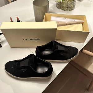 Axel arigato skor - Säljer mina Axel Arigato laceless i svart färg, storlek 45. Allt og medföljer. Sparsamt använda i Stockholm stad ett fåtal gånger. Inköpta i Arigato butiken i Stockholm för 2200kr - mitt pris: 1000kr. Kvitto finns. Liten fläck vid tårna på vänster sko. 