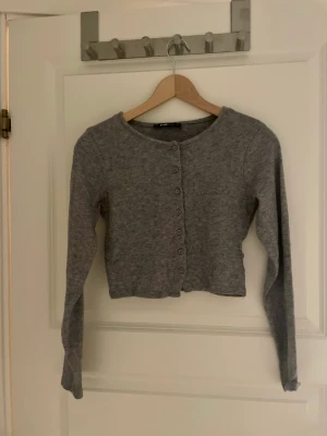 Grå kofta-New Yorker stl S - Grå kofta från New Yorker,stl S. Säljer eftersom den inte kommer till användning. Mjuk och använd max 5 ggr. Endast Swish. 80kr Inkl frakt.