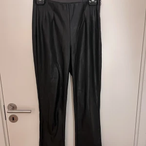 Byxor - Skinnbyxor (fejk) med dragskedja i sidan och nere vid benslutet. Sitter väldigt fint på, utsvängda vid foten.