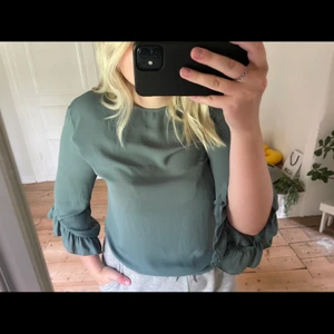 Blus - Grön blus med volang arm som slutar vid armveckena ungefär från Gina tricot 