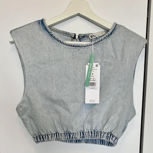Denimtop  - Crop topp i denim med dragkedja baktill. Ljusblå i verkligheten, ser lite grå ut på bild💙 Skick: oanvänt. 100 % Ekoligisk bomull. ”Kontakta” om du undrar något. ”Köp nu” om du är redo att köpa