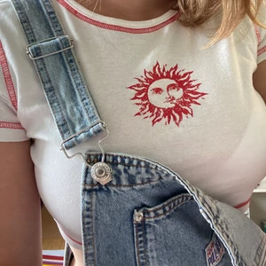 Crop topp med sol - Vit croppad top med röda sömmar och en sol 🌞 Vit som på första bilden. Storlek S i H&Ms divided. Skick: bra / använt några gånger. ”Kontakta” om du undrar något. ”Köp nu” om du är redo att betala.