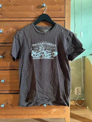 Brun T-shirt - Brun T-shirt från Polo Ralph Lauren. Köpt second hand, är i ganska bra skick. Size S, men är liten i storleken så kan passa XS. Skicka DM vid frågor. Spana in mina andra annonser också!