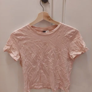 H&M, S - En rosa t-shirt med ett broderat rosa hjärta. Använt ett fåtal gånger och är i bra skick. Den är i st S från H&M. 25kr+frakt