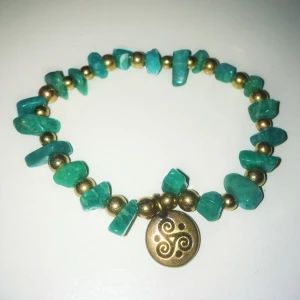 Armband Amazonite Brons Keltisk triskele - Handgjort (av mig) armband med bronsaktiga pärlor, stenar i amazonite och ett bronshänge med en keltisk triskele. Skapat med inspiration av land, hav och luft. 🌬🌊 Armbandets omkrets är 22 cm. Det är elastiskt för att enkelt kunna träs över handen. ✋🏼✋🏿✋🏽