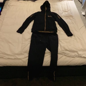 Hugo Boss Dress Svart/Guld - Säljer denna Svart/Guldiga Hugo Boss i samband med byxorna för ett bra pris  Båda är storlek S tröjan har inga fel alls bara tvättad ett antal gånger men hel osv Byxorna är skadade i snöret och högra fickan men dem ingår bara i priset