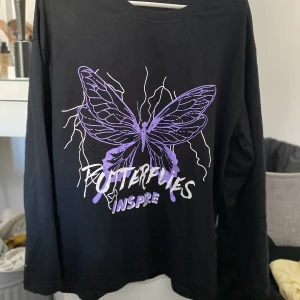 Långärmad tröja  - Svart långärmad ganska tunn skön tröja med lila och vitt tryck på. Lite längre och superfin, knappt använd. 40kr+frakt