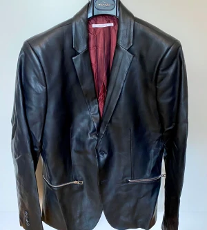 Calvin Klein faux leather blazer - I bought it at Macy’s in Miami Beach for $200. Never worn. Faux leather ultra slim fit with silver zippers. After storage in a case the collar got broken.