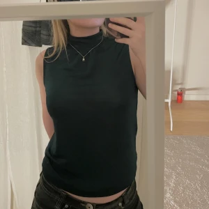 Topp - Finstickad mörkgrön topp som passar perfekt till fester. Om man tar bild med blixt syns lite glitter i tyget vilket syns på andra bilden. Säljs då jag rensar garderoben. (Nyskick)  Passar st S och M