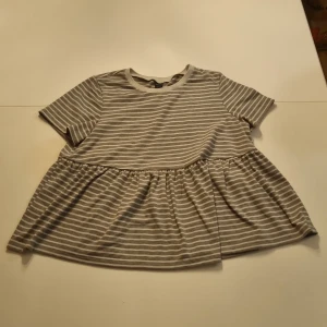 Tshirt - Gråvitrandig tshirt med volanger