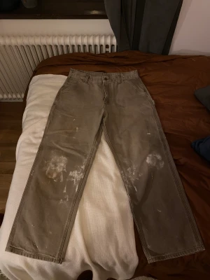 Carharrtt Carpenterpants - Ett par Carharrtt carptenterpants i storlek 36x32. De är använda ungefär 2 gånger och är i jättefint skick. Det är målarfärg på byxorna som ger en cool look. Mer bilder kan skickas vid önskan. 