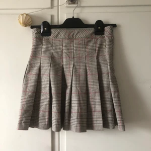 Veckad kjol (pleated skirt) - Använd fåtal gånger. Några lösa trådar men inget som syns eller påverkar kjolens passform. Knäpps med dragkedja och knapp på sidan.