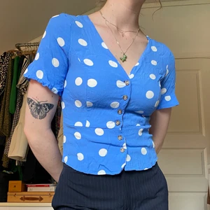 Säg prickig blå topp från Amisu i stl XS - Supersöt klarblå topp/blus med vitprickigt mönster och v-ringning samt knappstängning på framsidan. Från Amisu i stl XS men passar även S.  Du som köper står för frakt, möts annars upp vid Stockholm city.
