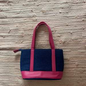 Marinblå handväska med rosa band. Jättefin söt liten handväska som får plats med mycket och har också en inner fack