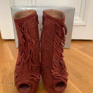 Werner vinröda mocka sandaletter med hög klack - Werner Brazilian Fotwear i vinröd mocka med fransar och högklack och platåtå i storlek 36 säljes för 400kr. Jag kan träffas i Stockholm city eller så trycker du på köp knappen så skickar jag dem till dig.