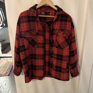 ZARA rödrutig skjortjacka oversize - Tjockare skjorta/skjortjacka, eller overshirt, från Zara i rödsvart rutmönster. Använd endast ett par gånger och köpt för ca 600 kr. Storlek S men oversize i modellen och skulle passa även en M bra.