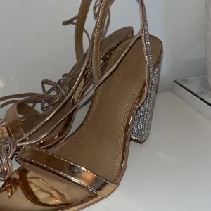 Rhinestone klackskor rosé guld - Helt otroliga Roseguldiga klackskor med rhinestones och snörning från asos wide fit storlek 37. Använda en gång i fem minuter för student bilder. Köpta för ca 500kr säljes då de tyvärr inte kommer till användning